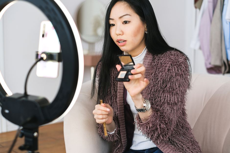 Young woman recording a makeup tutorial with a ring light for her vlog.
