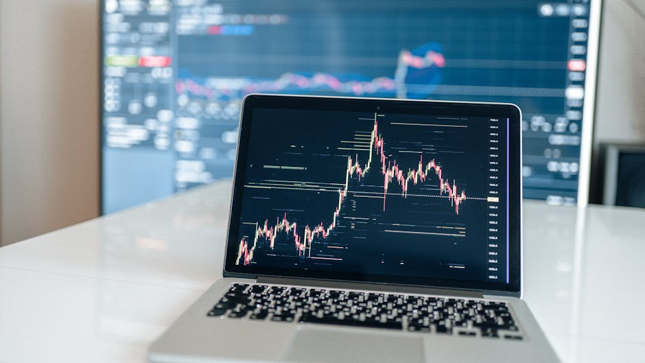 Laptop displaying cryptocurrency trading chart on a white desk.