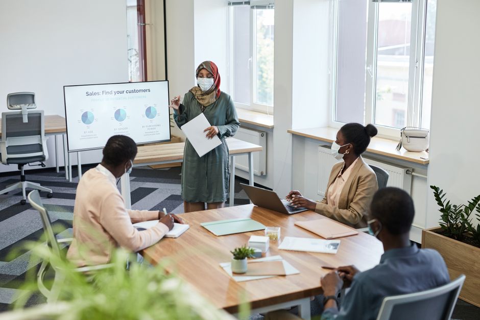 Business professionals in a COVID-safe office meeting, discussing sales strategies.