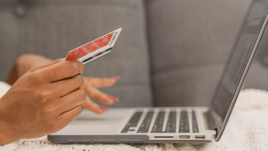 Close-up of a person using a credit card for online shopping on a laptop.