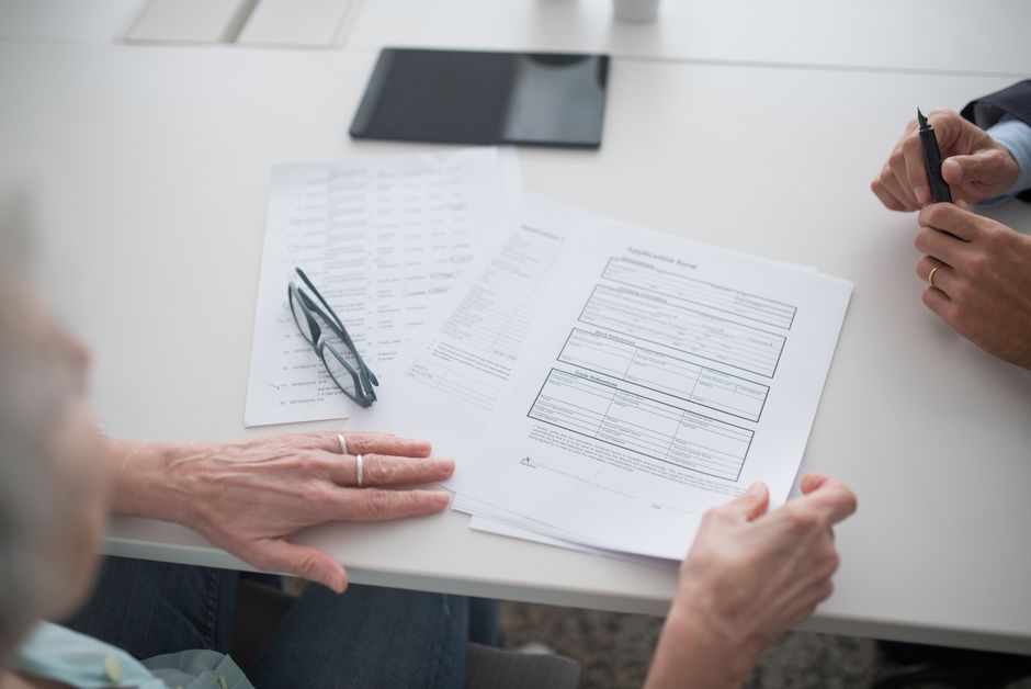 Close-up view of two individuals reviewing documents and forms in an office setting.